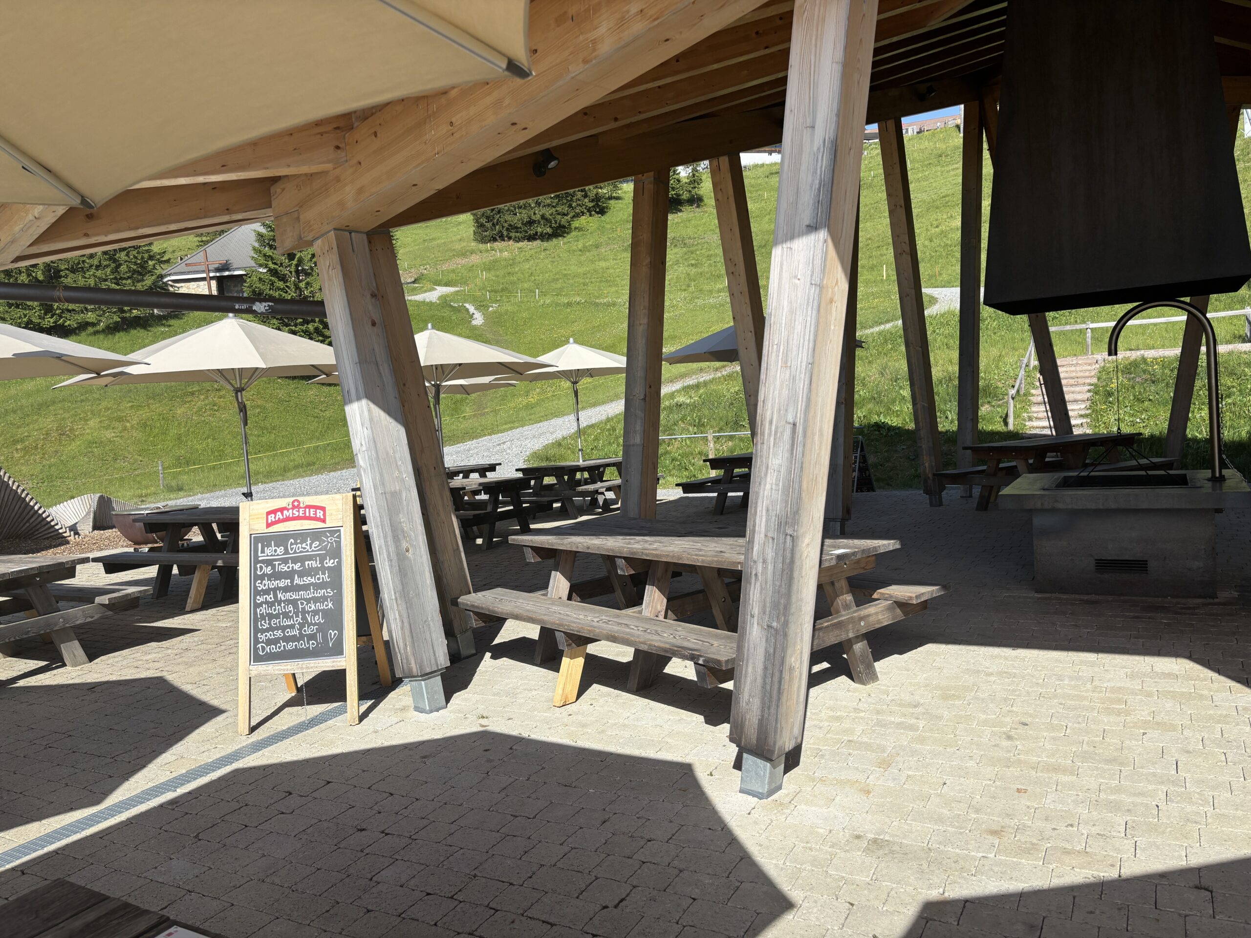 Überdachter Picknick- und Rastplatz auf der Drachenalp bei Fräkmüntegg am Pilatus mit Holztischen und Grillstelle.